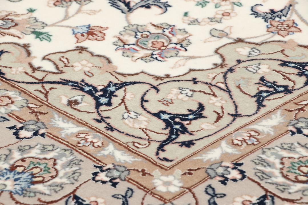 Et håndknyttet Isfahan-tæppe med blomstermedaljonmønstre i beige og dæmpede toner.