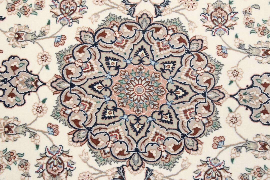 Et håndknyttet Isfahan-tæppe med blomstermedaljonmønstre i beige og dæmpede toner.