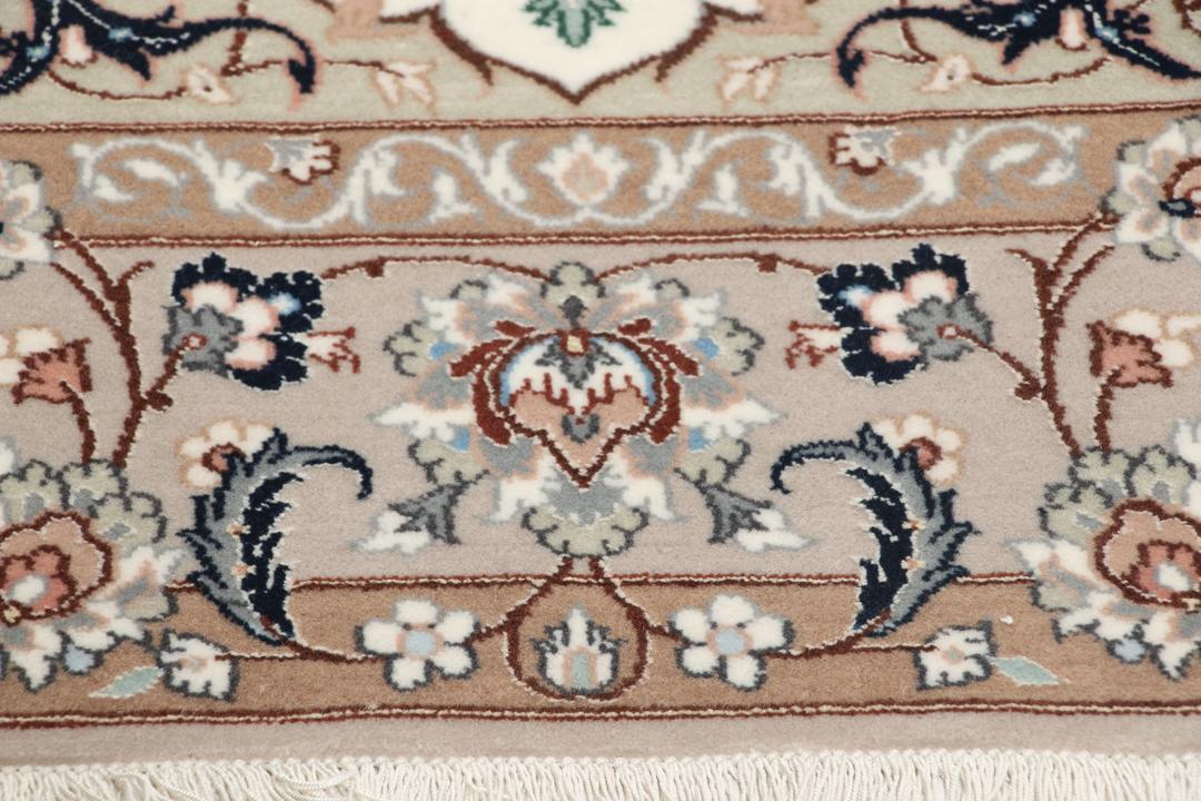 Et håndknyttet Isfahan-tæppe med blomstermedaljonmønstre i beige og dæmpede toner.
