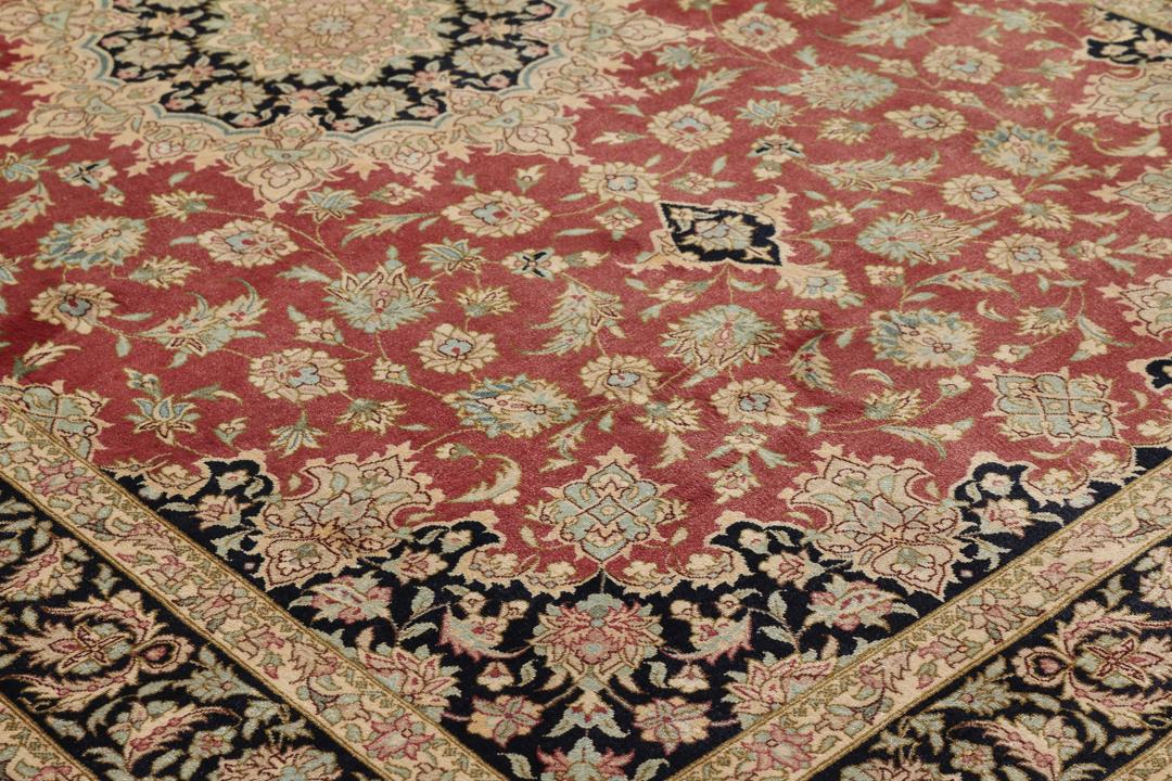 Een handgeknoopt Qum zijden tapijt uit het Midden-Oosten in rood- en zwarttinten.