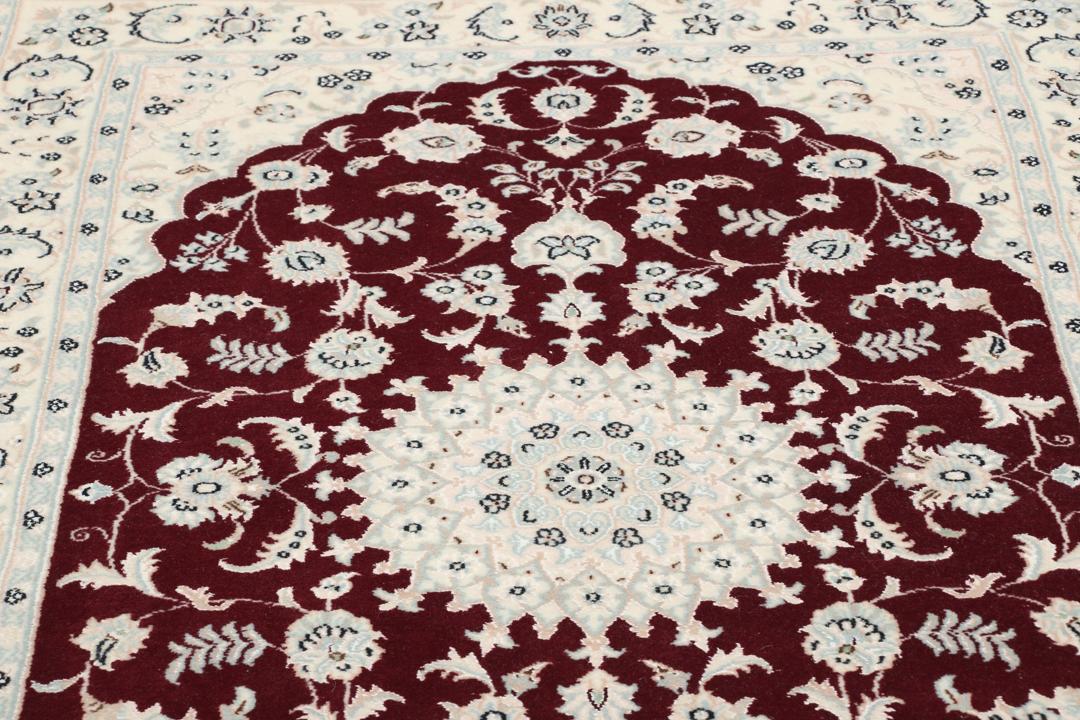 Een handgeknoopt Nain 9La tapijt uit het Midden-Oosten met een rood medaillon en een crèmekleurig veld