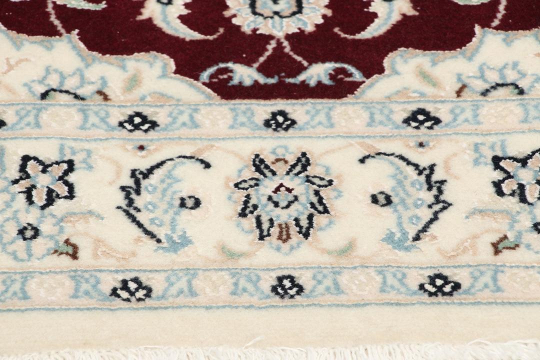 Een handgeknoopt Nain 9La tapijt uit het Midden-Oosten met een rood medaillon en een crèmekleurig veld