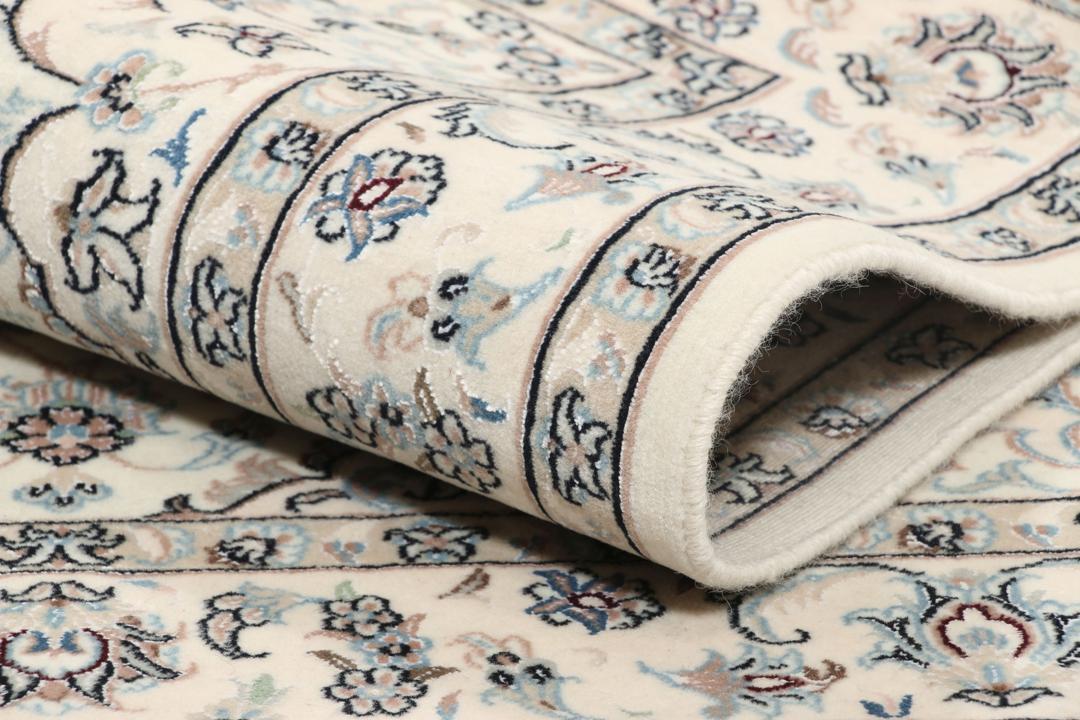 Et håndknyttet Nain-tæppe fra Mellemøsten med en beige bund og blomstermotiver.