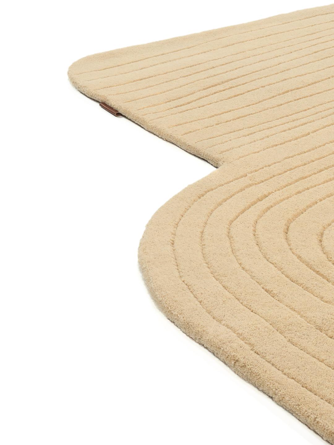 Beige tæppe med uregelmæssig form og høj og lav luv