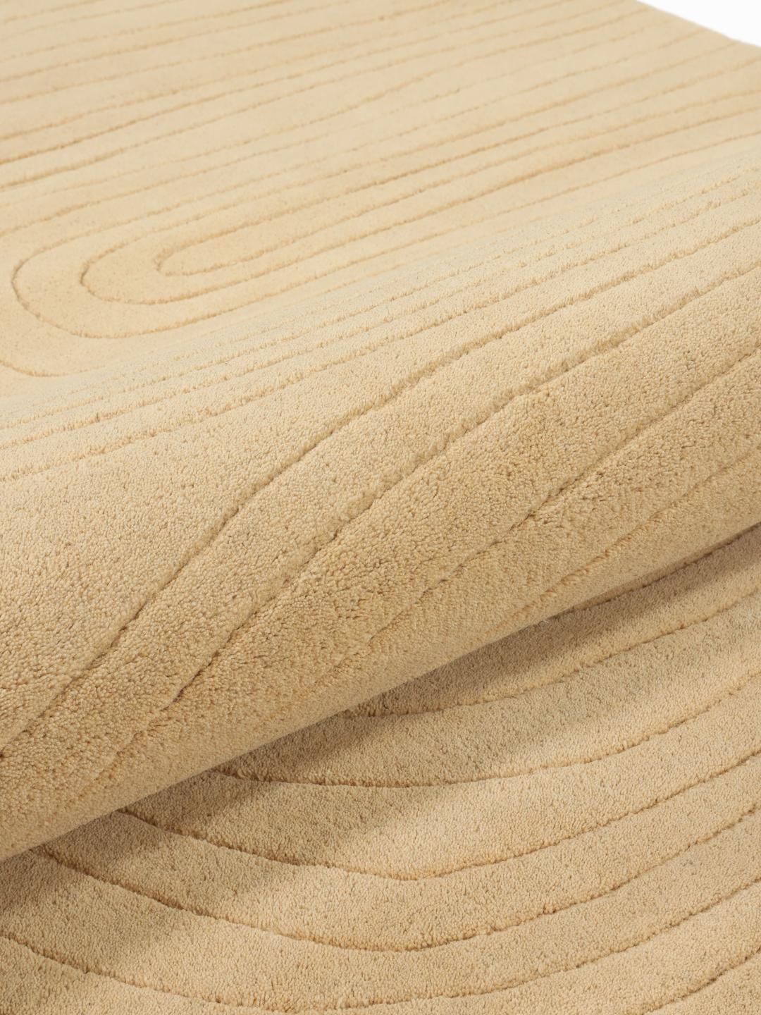Beige tæppe med uregelmæssig form og høj og lav luv