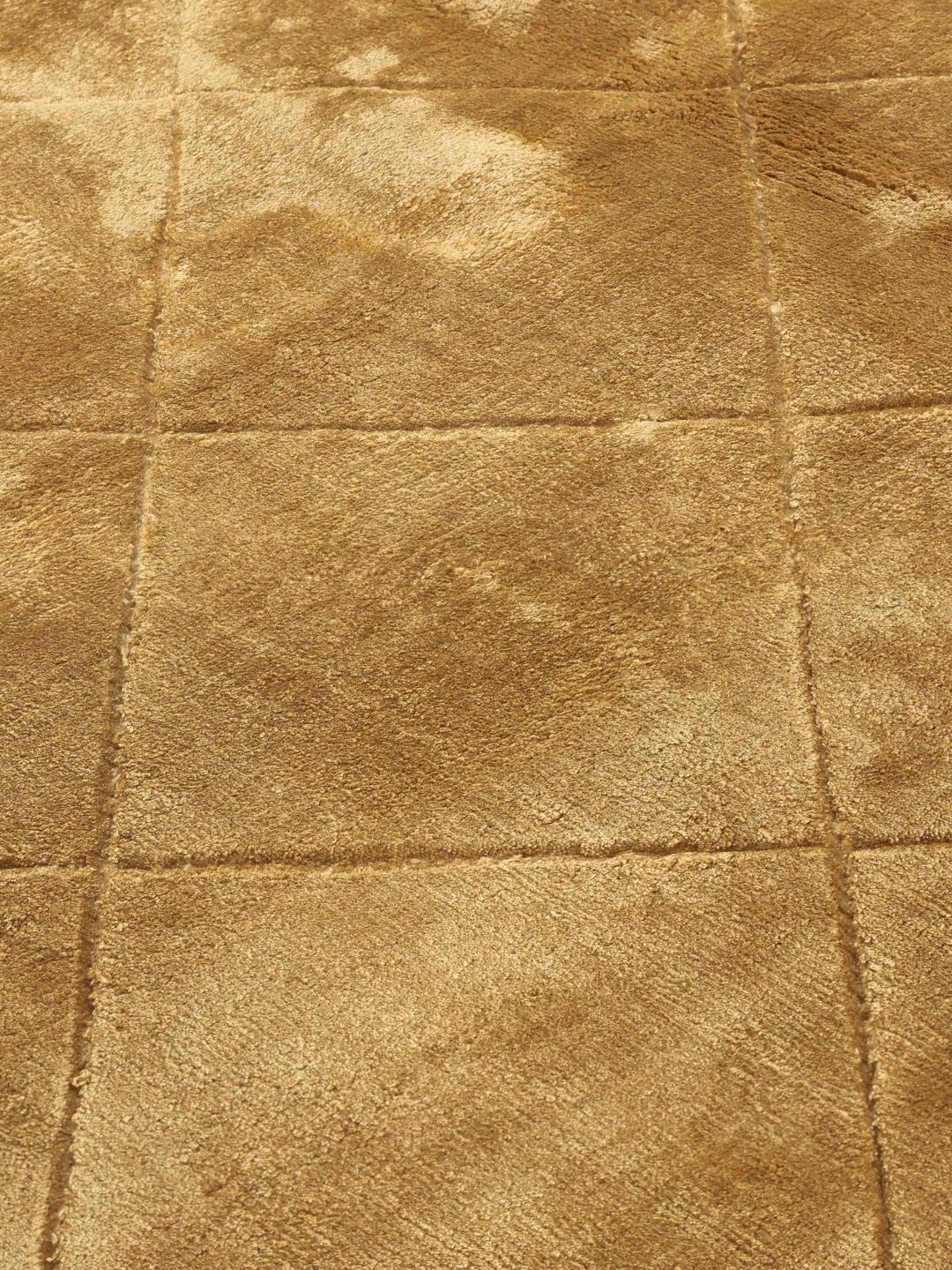 A brown rug with a diamond pattern in a warm golden tone.