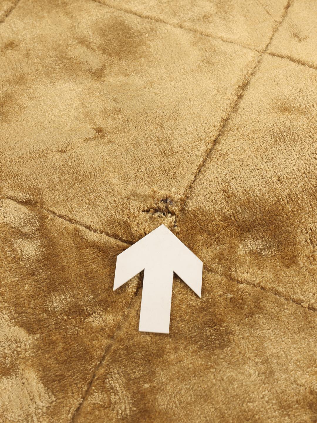 A brown rug with a diamond pattern in a warm golden tone.