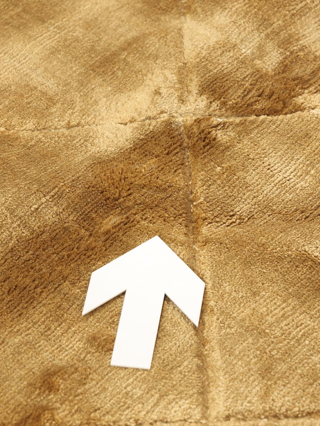 A brown rug with a diamond pattern in a warm golden tone.