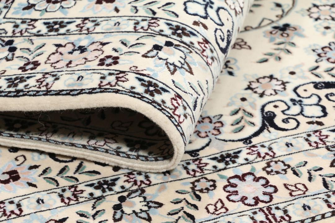 Handgeknoopt Nain tapijt uit het Midden-Oosten met ingewikkelde bloemmotieven in beige en blauw.