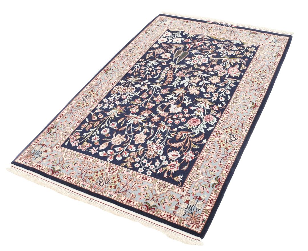 Een met de hand geknoopt Isfahan-tapijt met een ingewikkeld bloempatroon op een donkerblauw veld.