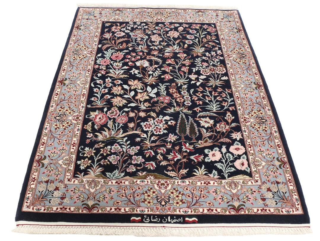 Een met de hand geknoopt Isfahan-tapijt met een ingewikkeld bloempatroon op een donkerblauw veld.