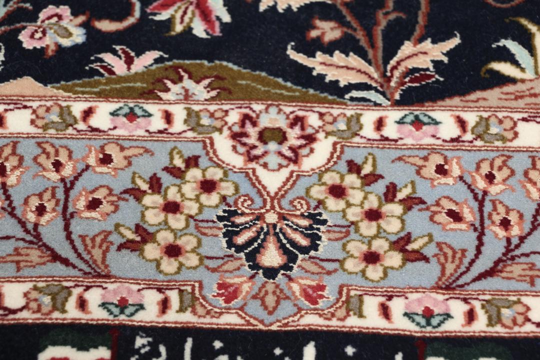 Een met de hand geknoopt Isfahan-tapijt met een ingewikkeld bloempatroon op een donkerblauw veld.