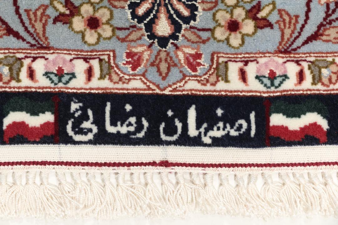 Een met de hand geknoopt Isfahan-tapijt met een ingewikkeld bloempatroon op een donkerblauw veld.