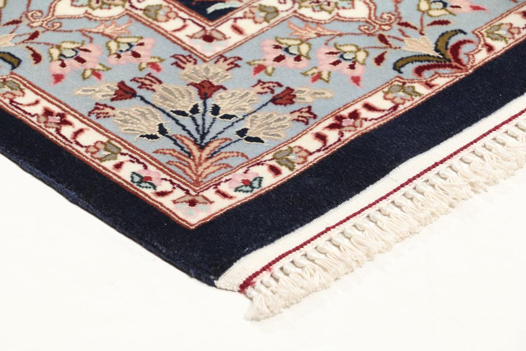 Een met de hand geknoopt Isfahan-tapijt met een ingewikkeld bloempatroon op een donkerblauw veld.