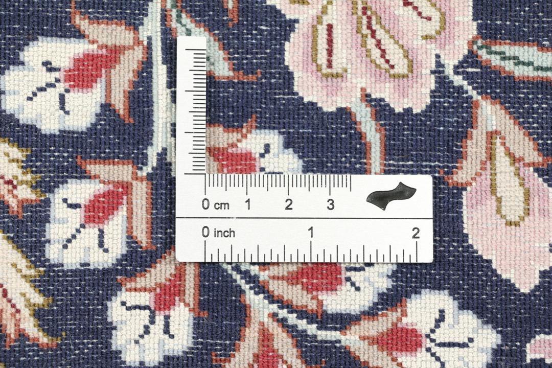 Een met de hand geknoopt Isfahan-tapijt met een ingewikkeld bloempatroon op een donkerblauw veld.