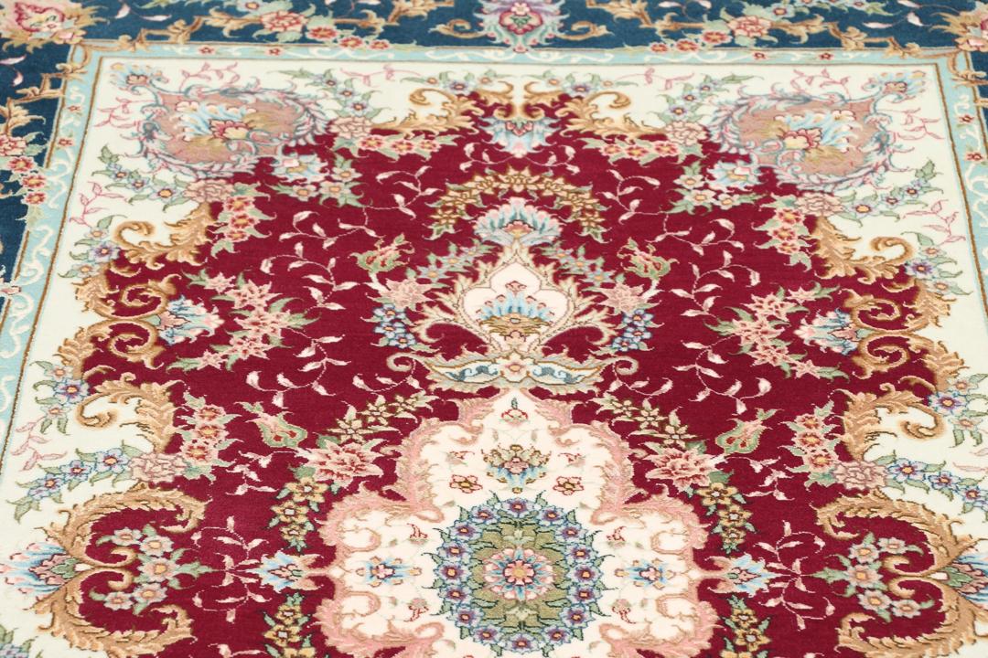 Et håndknyttet Tabriz tæppe fra Mellemøsten med en mørkerød baggrund og blomstermønstre.