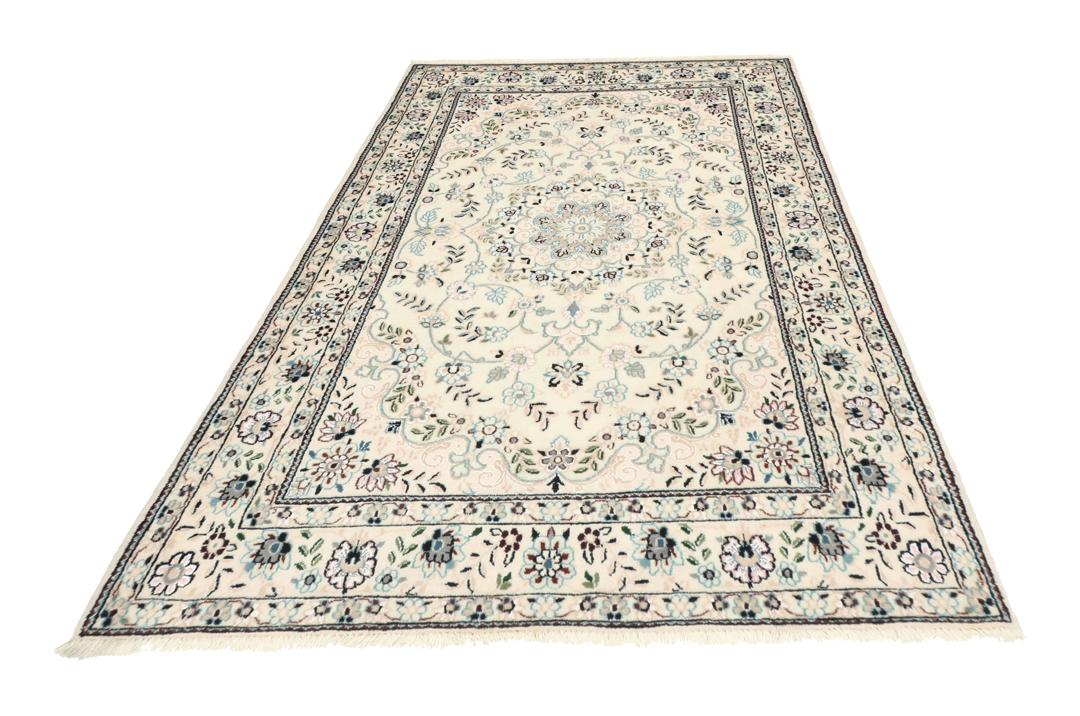 Een handgeknoopt Nain-tapijt uit het Midden-Oosten met een beige achtergrond en bloempatronen.