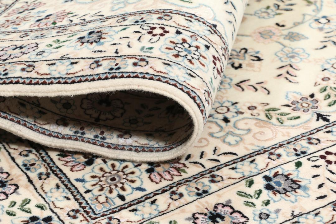 Een handgeknoopt Nain-tapijt uit het Midden-Oosten met een beige achtergrond en bloempatronen.