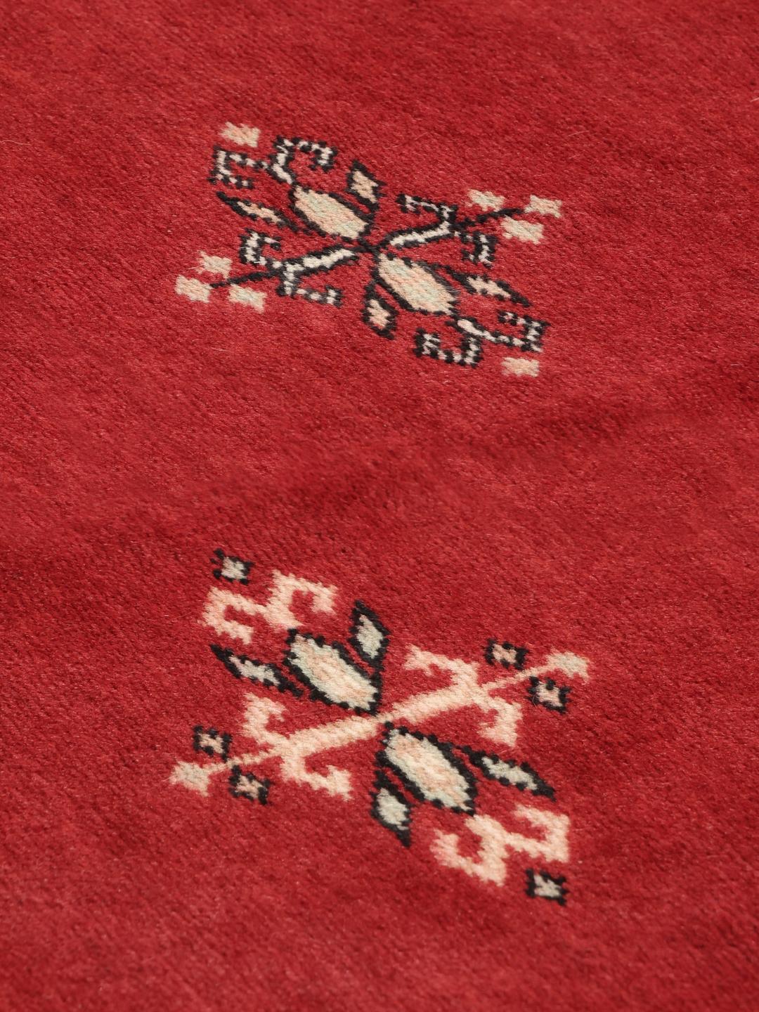Hand-knotted Pakistan Bokhara rug with a deep red field and traditional motifs.