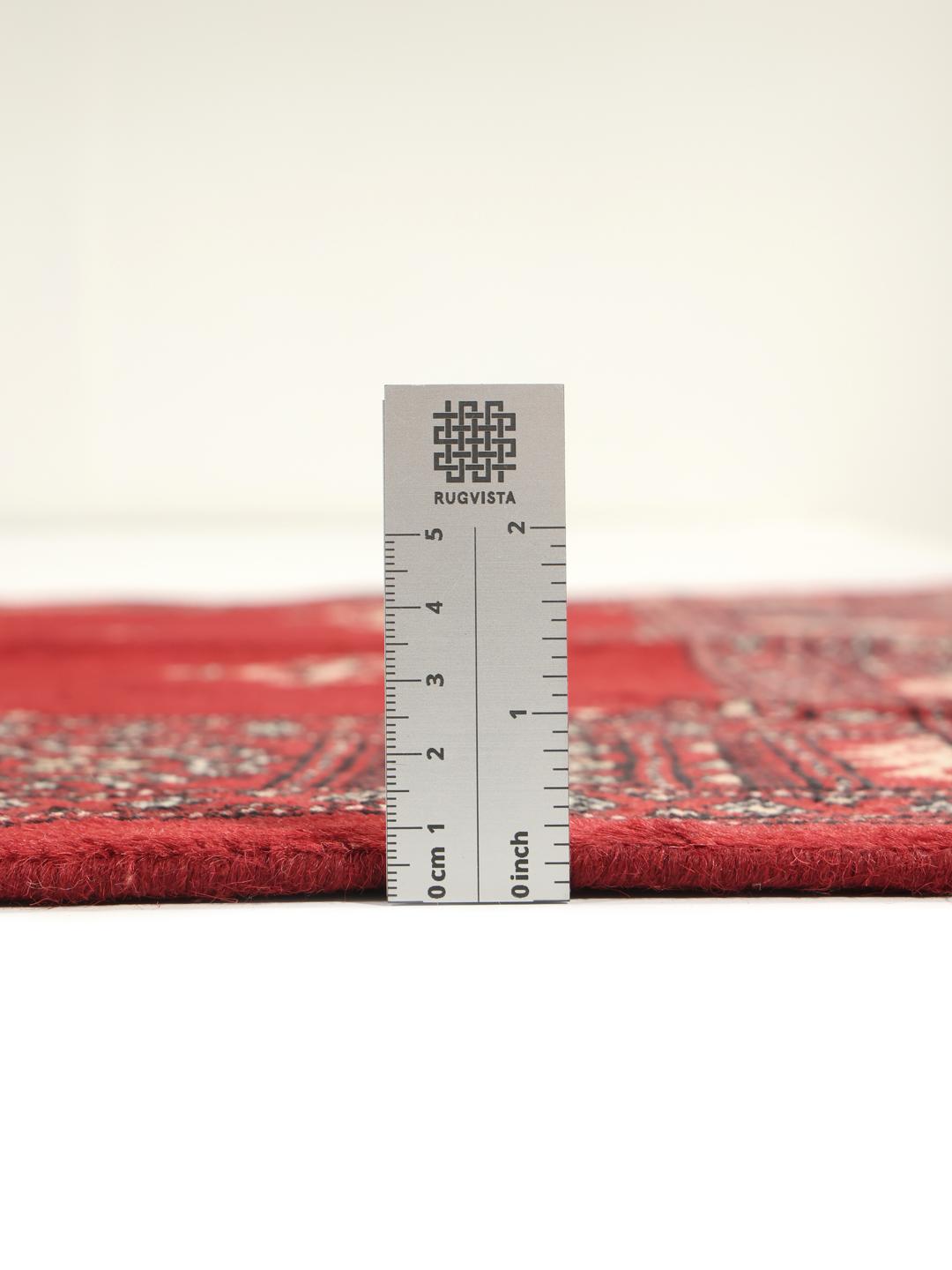 Hand-knotted Pakistan Bokhara rug with a deep red field and traditional motifs.