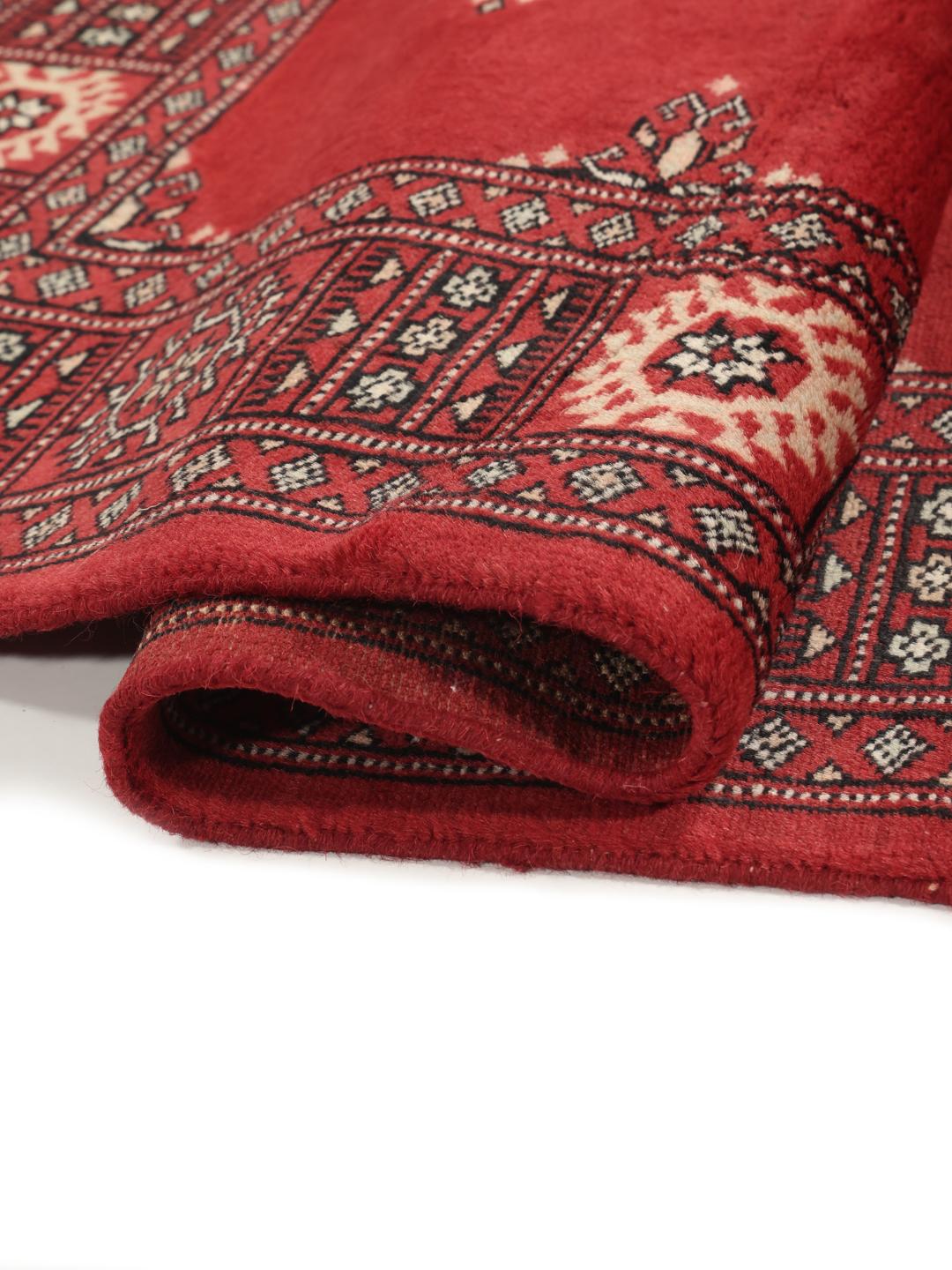 Hand-knotted Pakistan Bokhara rug with a deep red field and traditional motifs.
