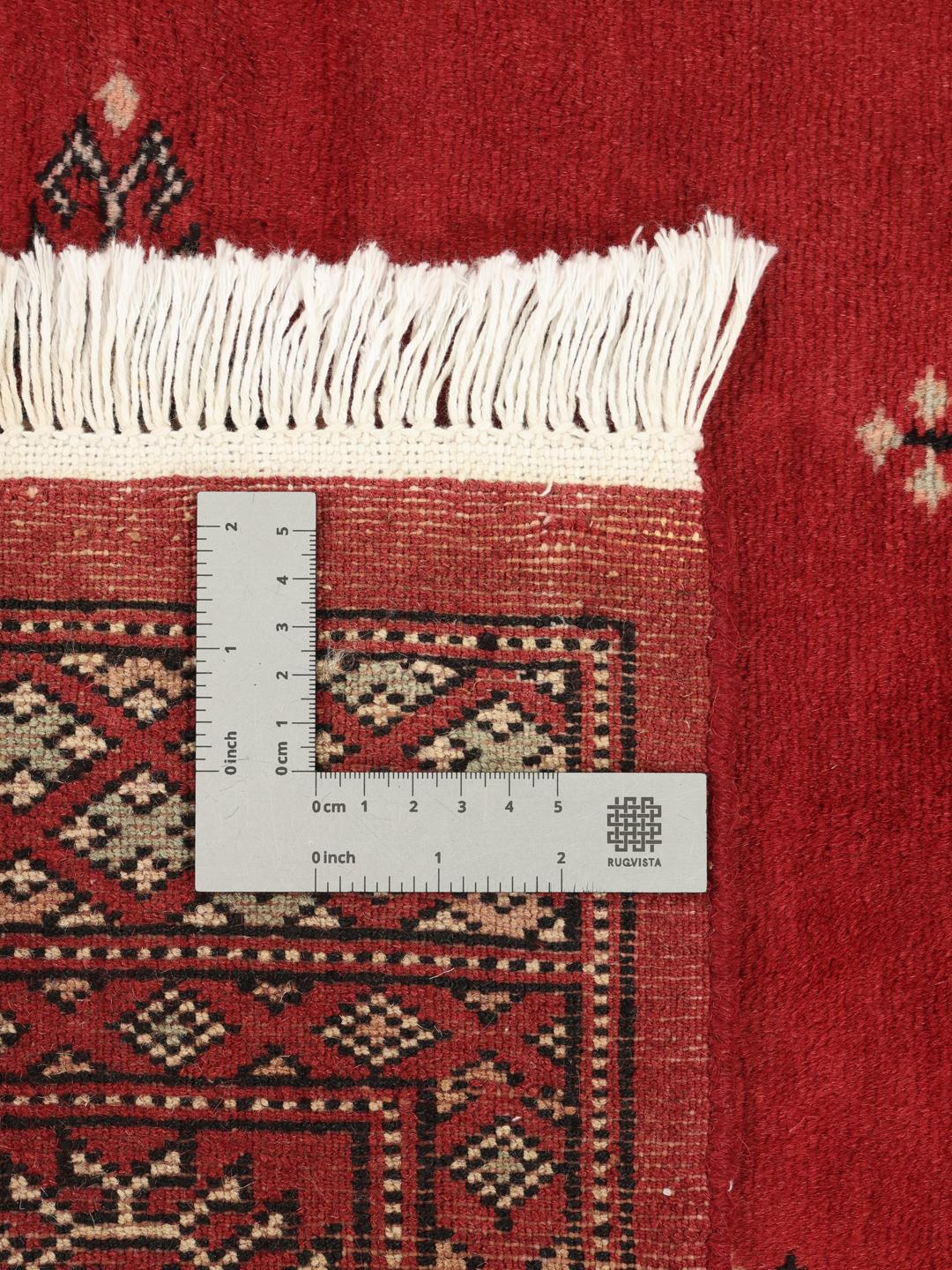 Hand-knotted Pakistan Bokhara rug with a deep red field and traditional motifs.
