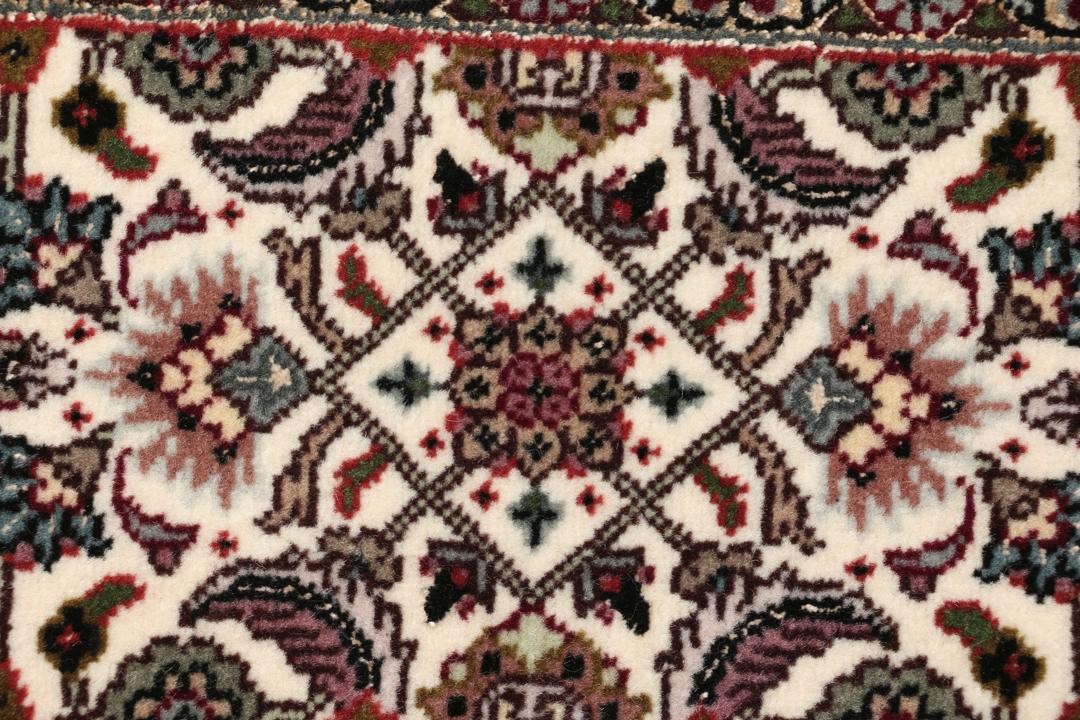 Et rektangulært Tabriz-tæppe fra Mellemøsten med et mørkt, flerfarvet blomsterdesign.