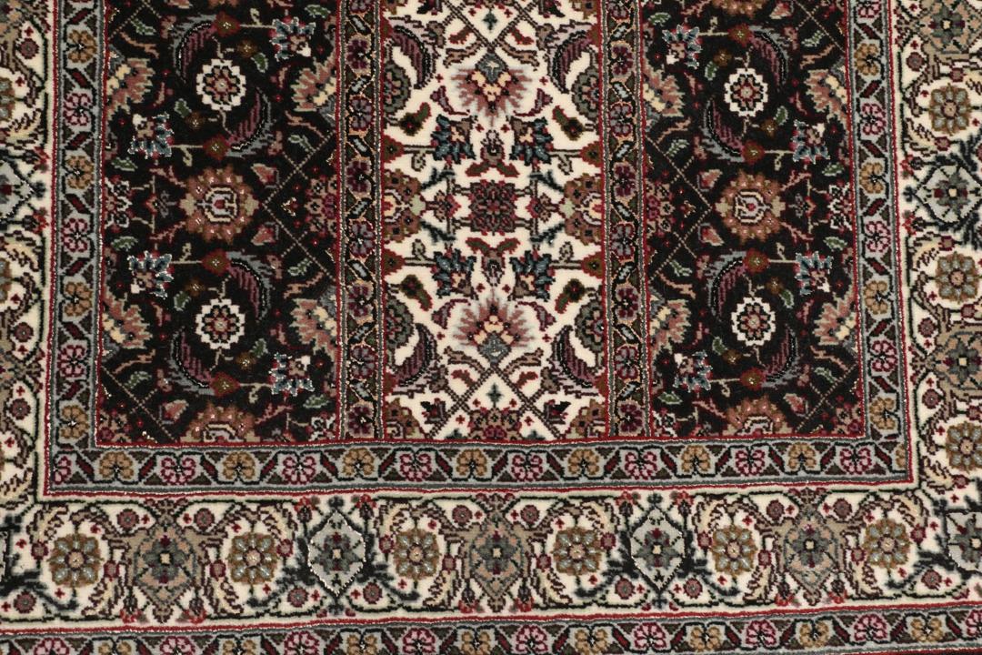 Et rektangulært Tabriz-tæppe fra Mellemøsten med et mørkt, flerfarvet blomsterdesign.