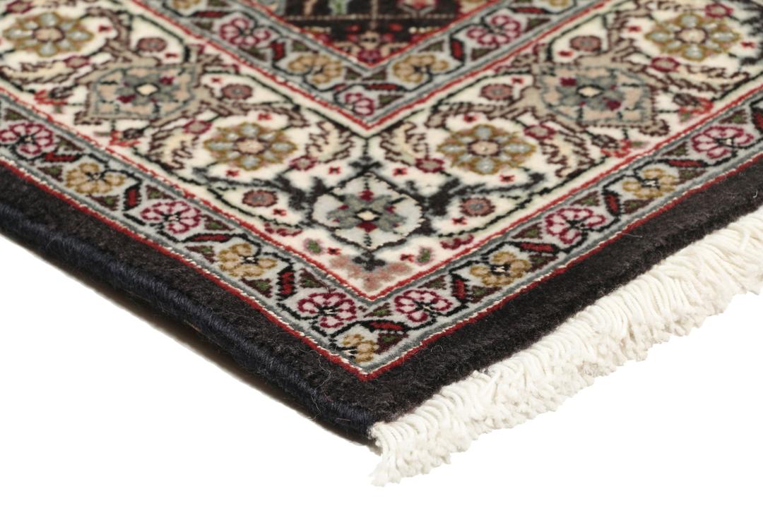 Et rektangulært Tabriz-tæppe fra Mellemøsten med et mørkt, flerfarvet blomsterdesign.