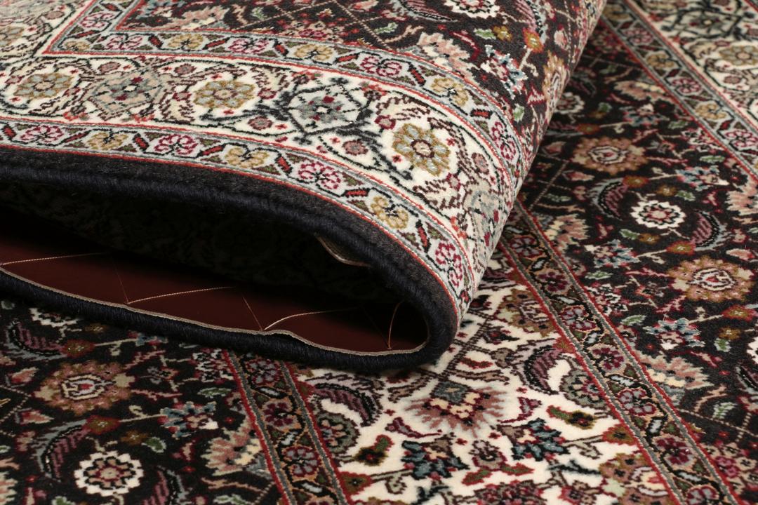 Et rektangulært Tabriz-tæppe fra Mellemøsten med et mørkt, flerfarvet blomsterdesign.