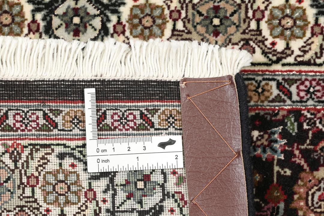 Et rektangulært Tabriz-tæppe fra Mellemøsten med et mørkt, flerfarvet blomsterdesign.