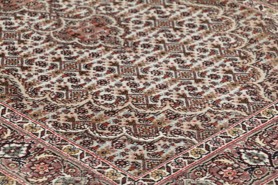 Et håndknyttet Tabriz-tæppe fra Mellemøsten med et rødt og beige blomster-medaljondesign.