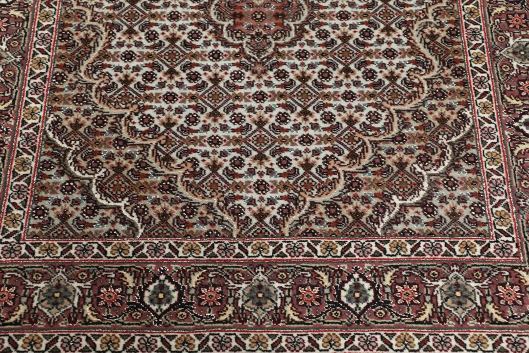 Et håndknyttet Tabriz-tæppe fra Mellemøsten med et rødt og beige blomster-medaljondesign.