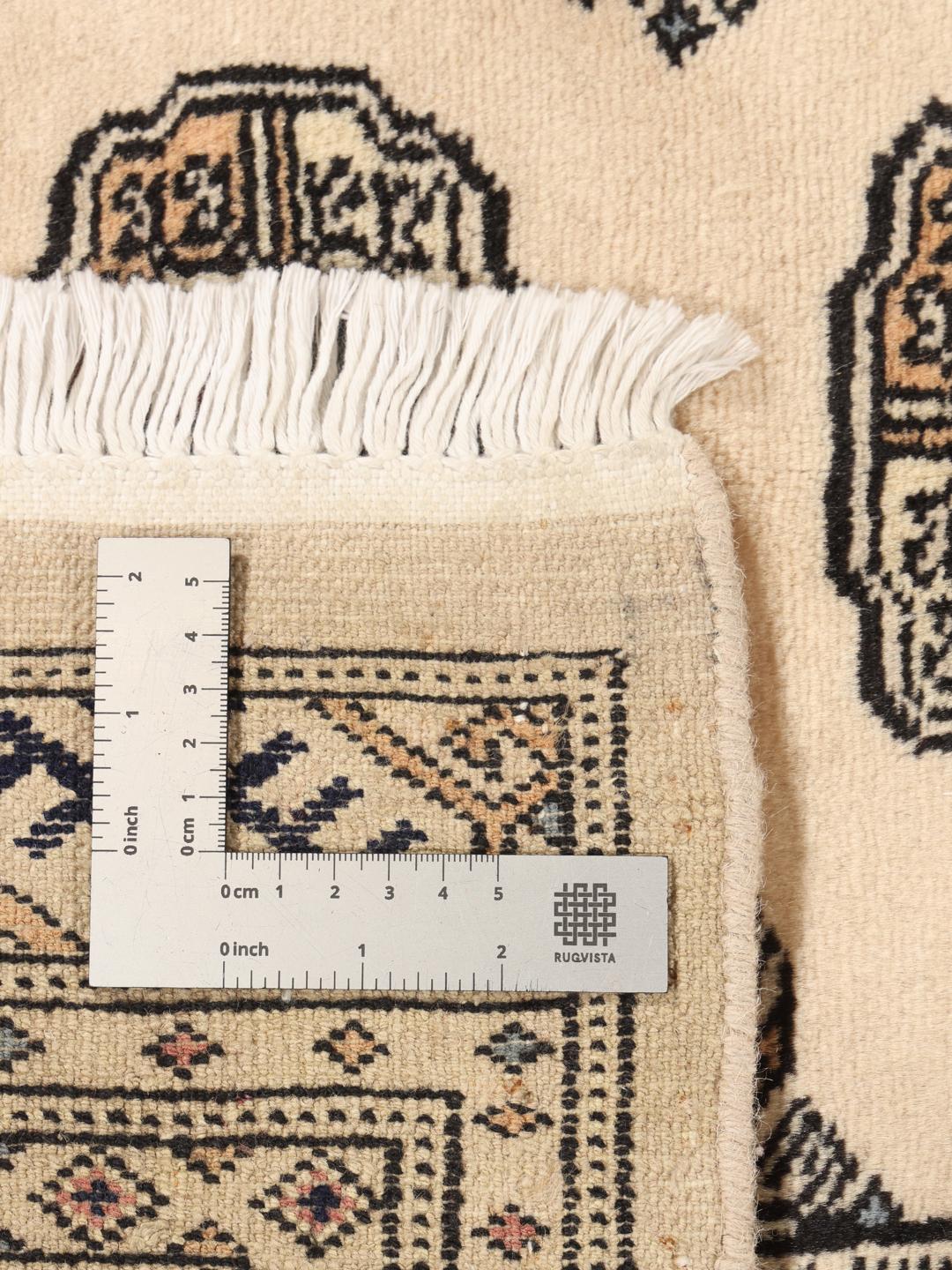 A hand-knotted Pakistan Bokhara 2ply rug with a beige field and traditional repeating motifs.