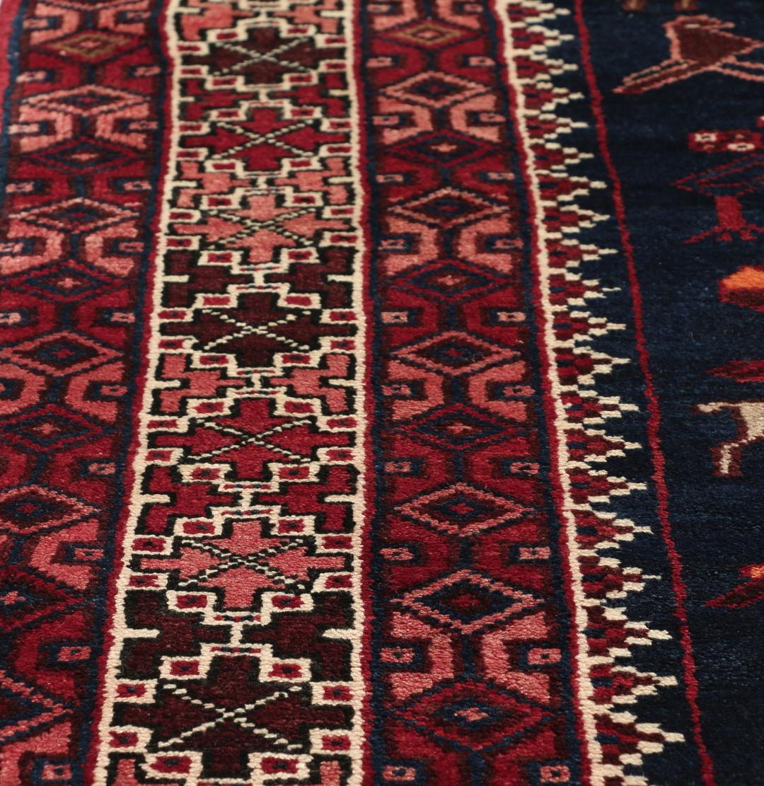 Een uniek, met de hand geknoopt Kurdi Ghuchan tapijt uit het Midden-Oosten met een donkerblauw veld en gedetailleerde diermotieven.