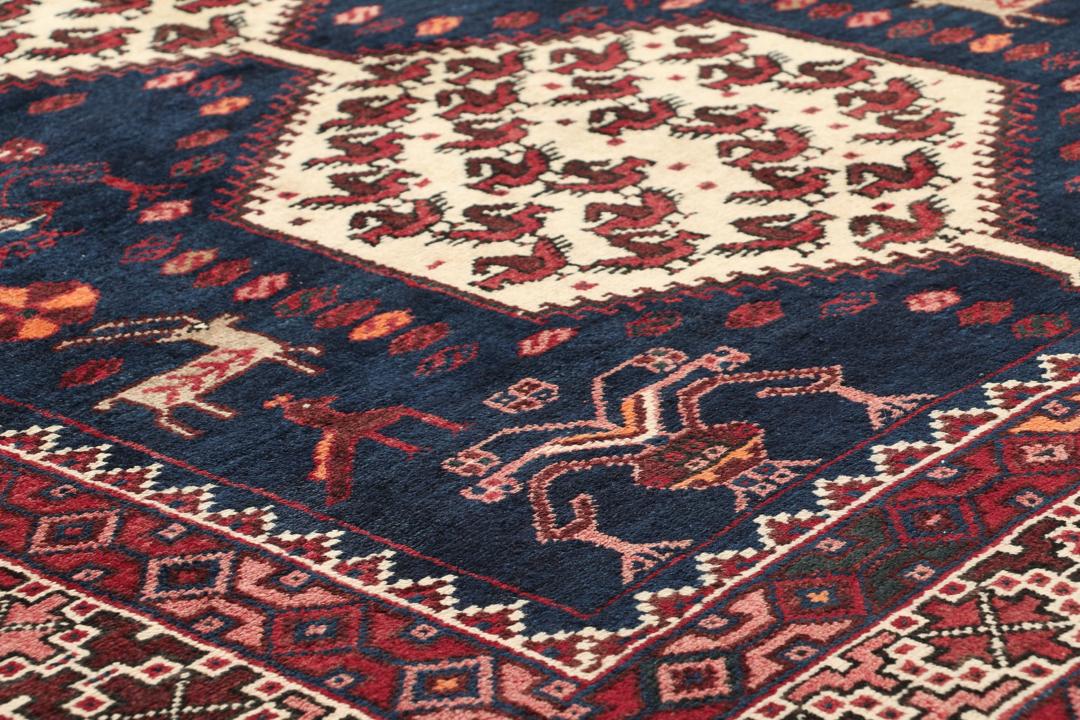 Een uniek, met de hand geknoopt Kurdi Ghuchan tapijt uit het Midden-Oosten met een donkerblauw veld en gedetailleerde diermotieven.