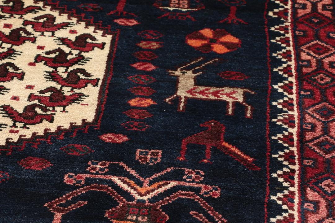 Een uniek, met de hand geknoopt Kurdi Ghuchan tapijt uit het Midden-Oosten met een donkerblauw veld en gedetailleerde diermotieven.