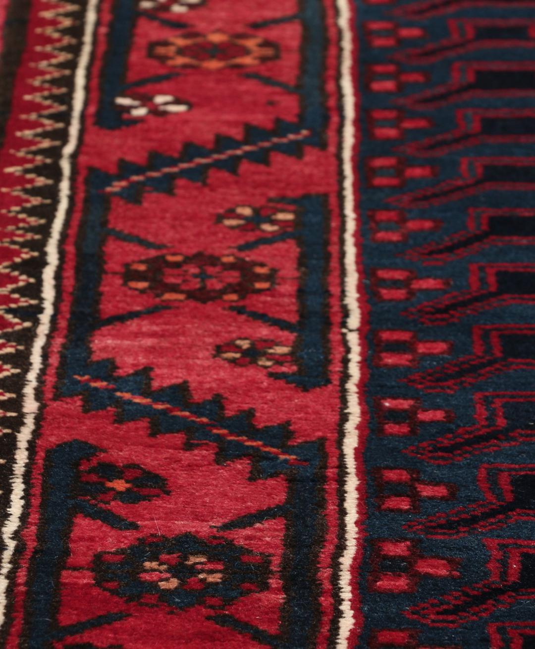 Een handgeknoopt Zanjan-tapijt uit het Midden-Oosten met een dieprood en zwart geometrisch ontwerp.