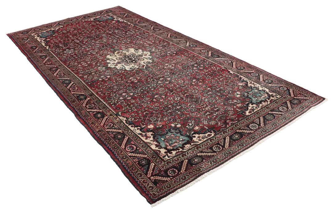 Handgeknoopt Nahavand-tapijt met een donkerrood veld en traditionele bloemmotieven.