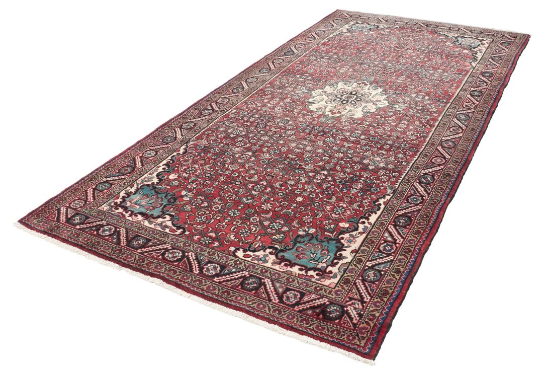 Handgeknoopt Nahavand-tapijt met een donkerrood veld en traditionele bloemmotieven.
