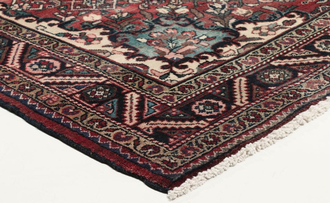 Handgeknoopt Nahavand-tapijt met een donkerrood veld en traditionele bloemmotieven.