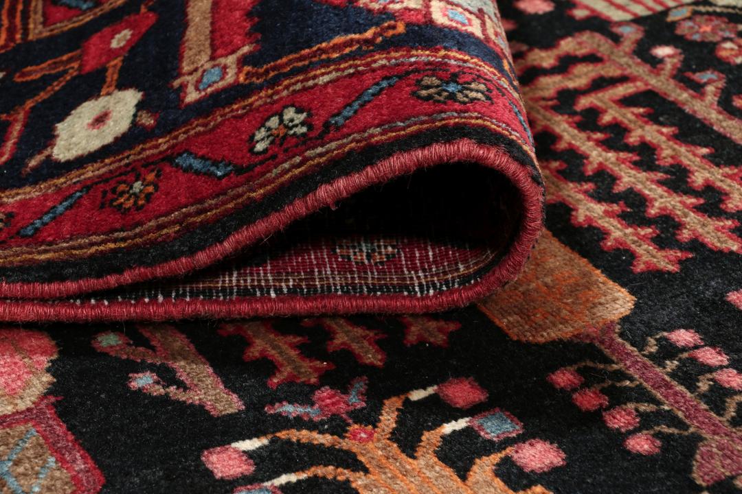 Handgeknoopt Kurdi Ghuchan-tapijt uit het Midden-Oosten met een veelkleurig tribaal patroon op een donker veld