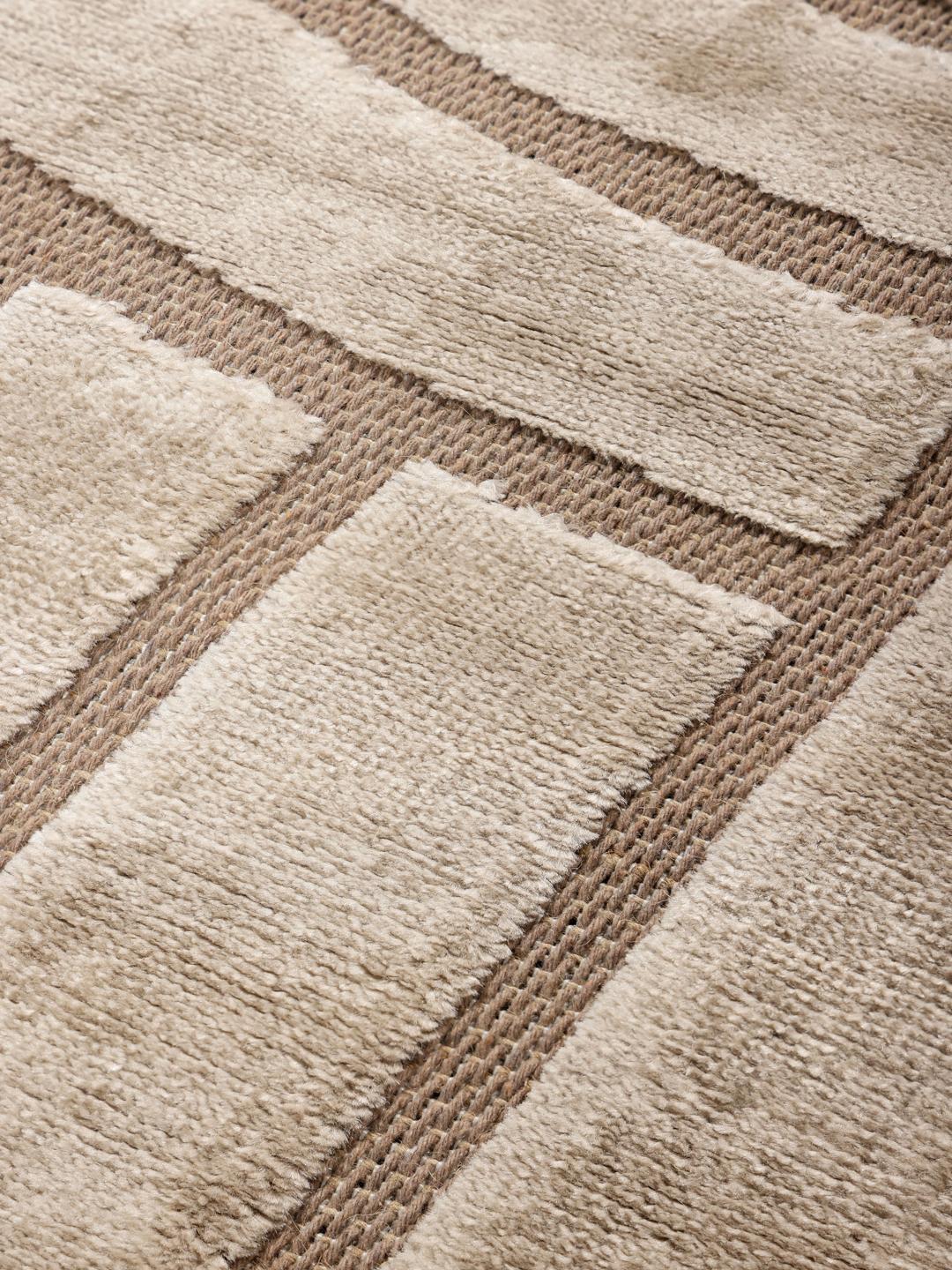 Onregelmatig beige vloerkleed met een modern hoog-laag geometrisch patroon