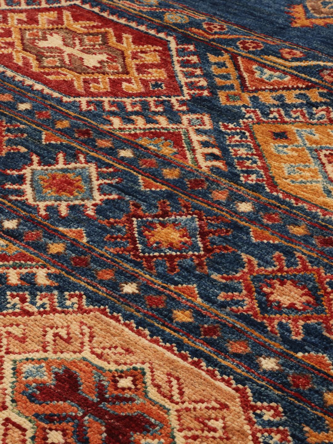 Alfombra afgana anudada a mano con un campo azul intenso y patrones geométricos intrincados