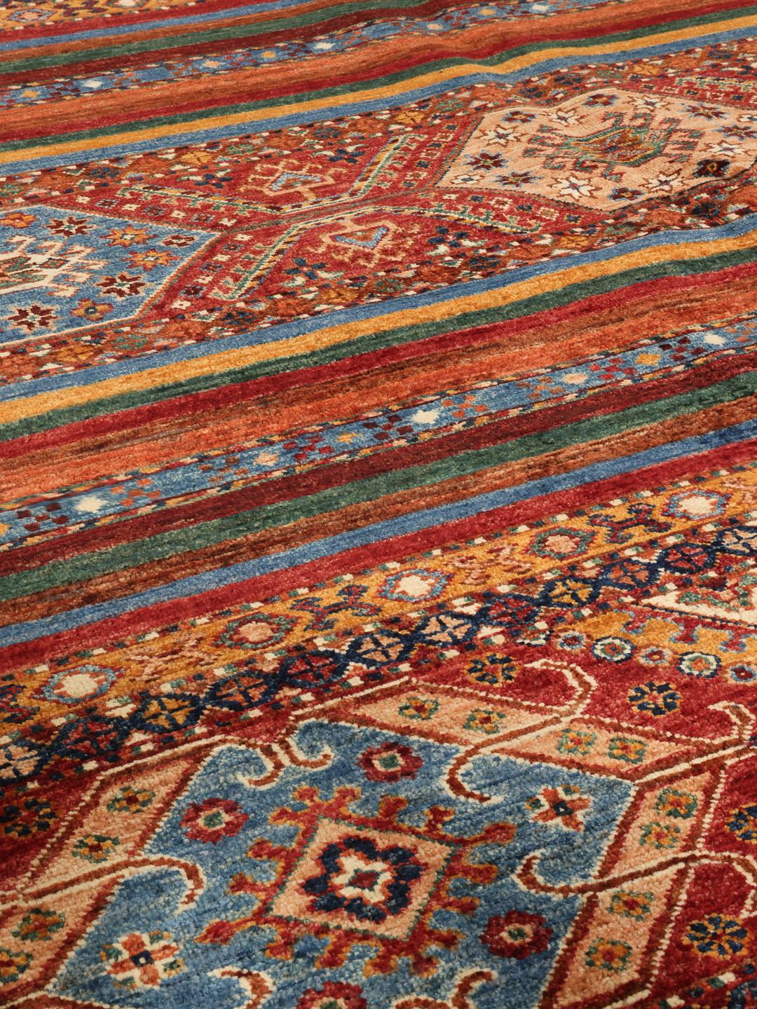 Handgeknoopt Afghaans tapijt met ingewikkelde geometrische patronen in rood, blauw en bruin.