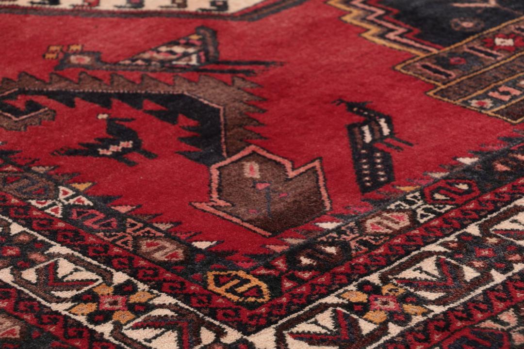 Et håndknyttet Afshar-tæppe fra Mellemøsten med et modigt rødt felt og geometriske motiver.