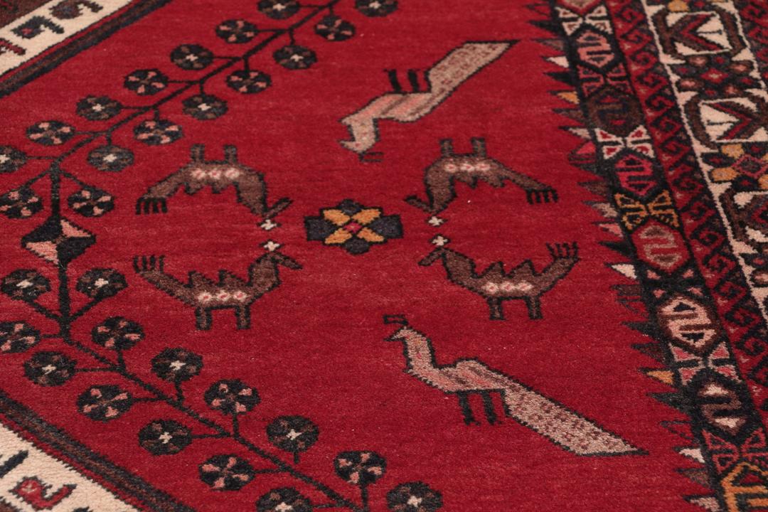 Et håndknyttet Afshar-tæppe fra Mellemøsten med et modigt rødt felt og geometriske motiver.
