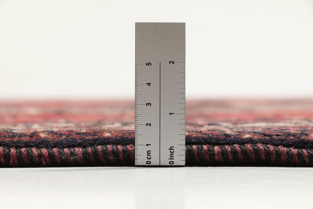 Et håndknyttet Afshar-tæppe fra Mellemøsten med et modigt rødt felt og geometriske motiver.