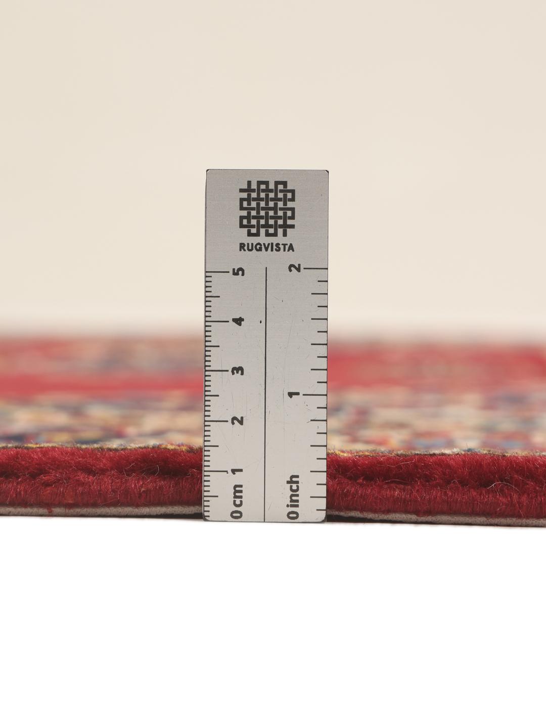 Een handgeknoopt Keshan tapijt uit het Midden-Oosten met een donkerrood veld en verfijnde florale details.