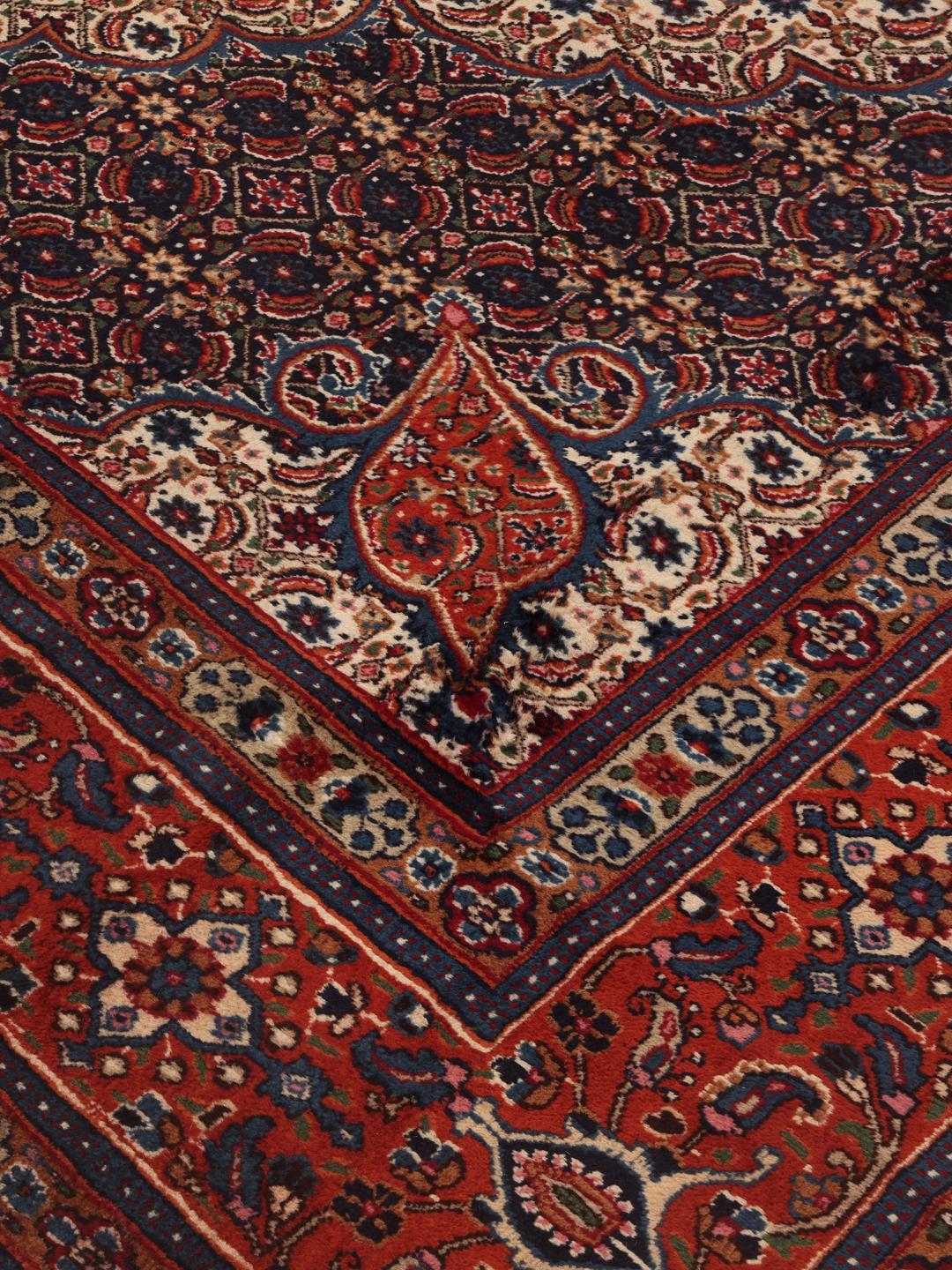 A hand-knotted Moud rug from the Middle East in dark-red and blue tones.